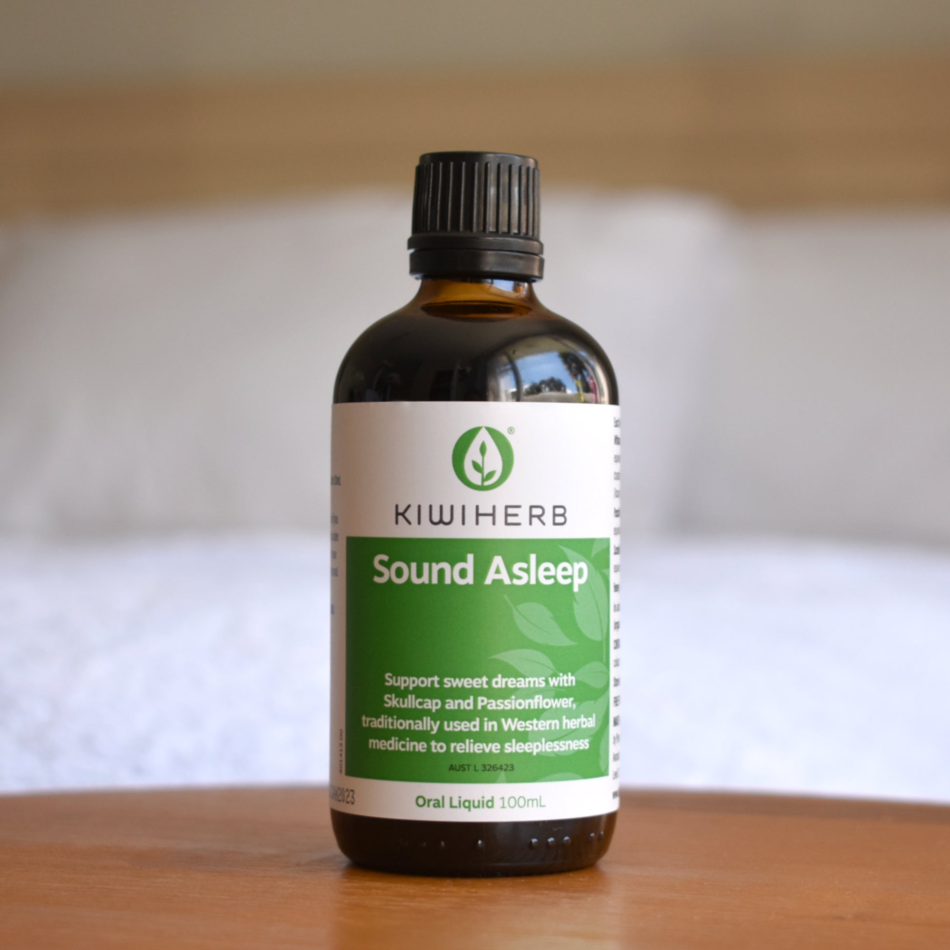 A bottle of Sound Asleep on a wooden bedside table.